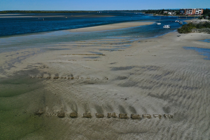 Aerial view of rusted oyster beds on sand