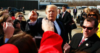 Donald Trump points as he is surrounding by a group of people.