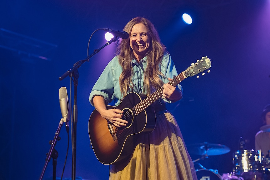 Kasey Chambers grins while playing guitar on stage at Bluesfest 2022