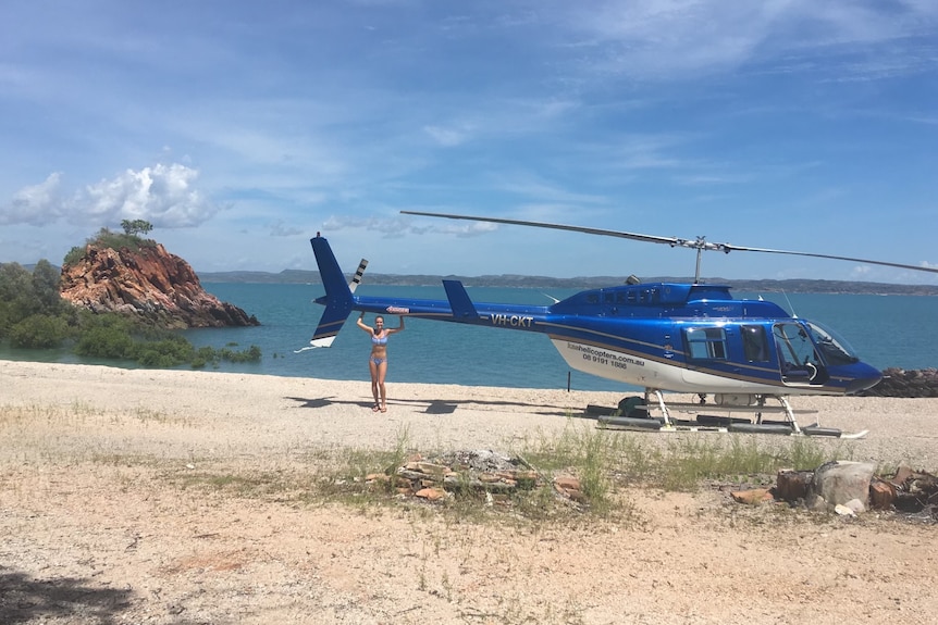 Callee Walsh stands next to a helicopter.