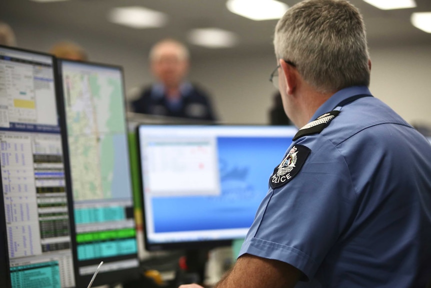 A police officer sits in front of a computer screen at the WA Police headquarters.