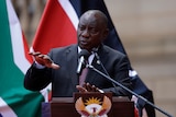 A man in a suit gestures at a lectern