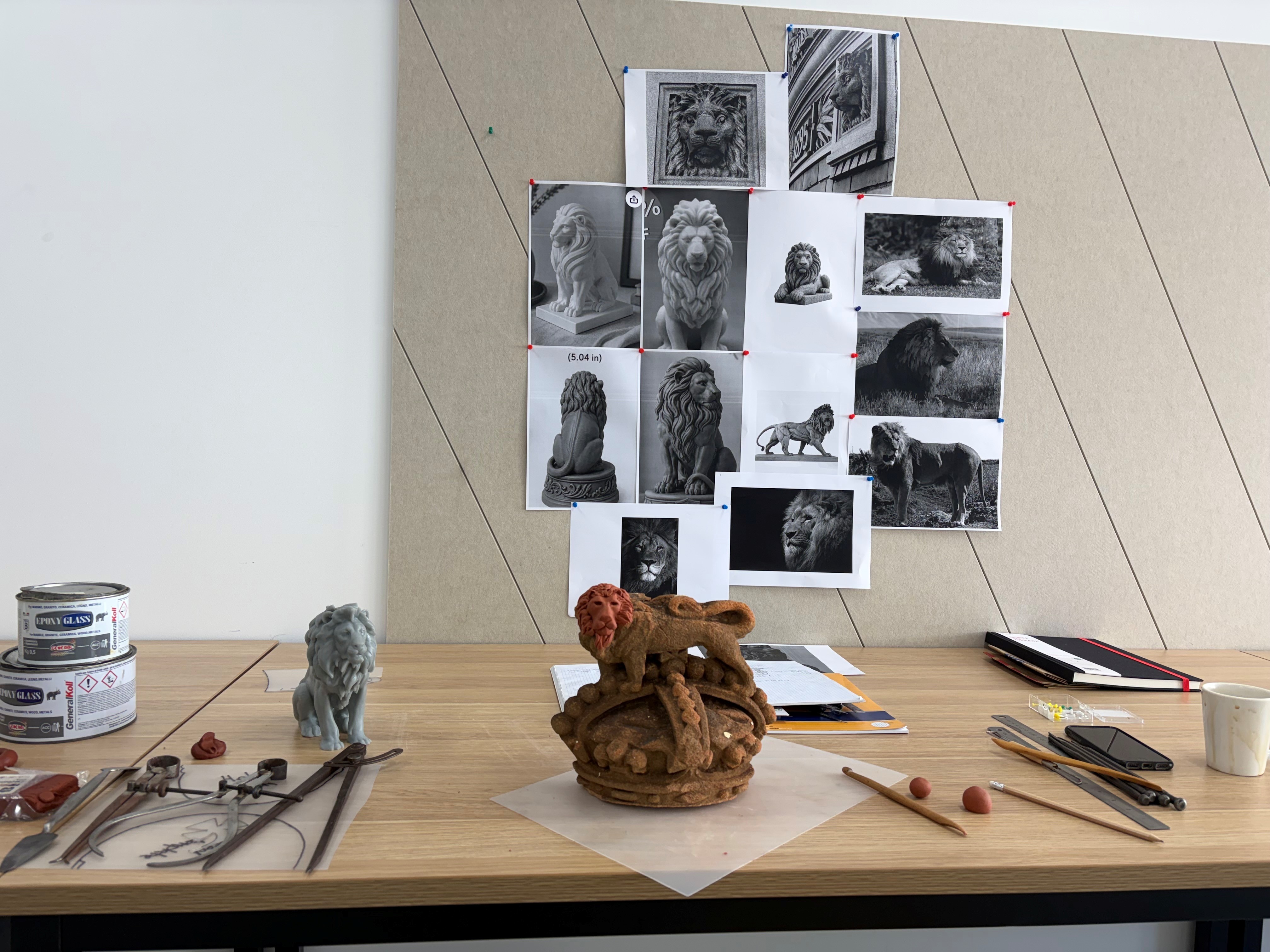 a model lion on a table surrounded by black and white photos of lions