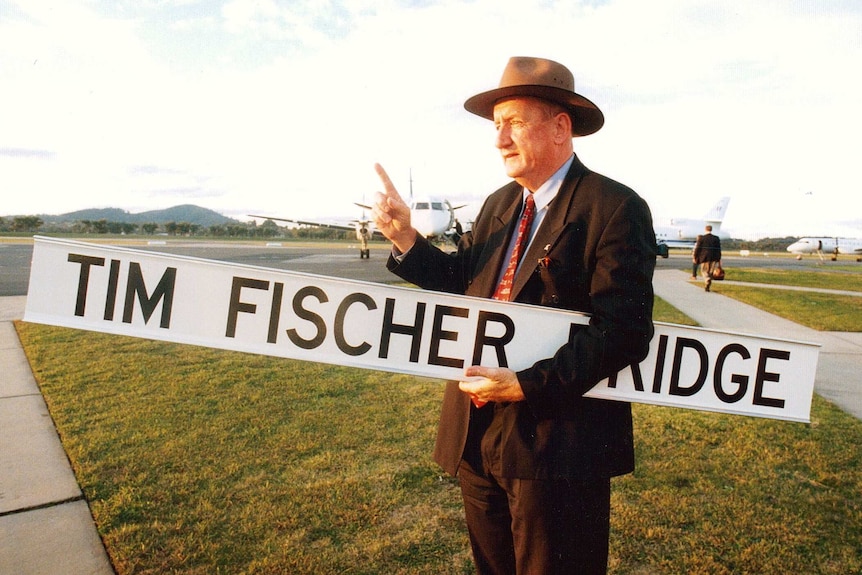 a man stands holding a long sign