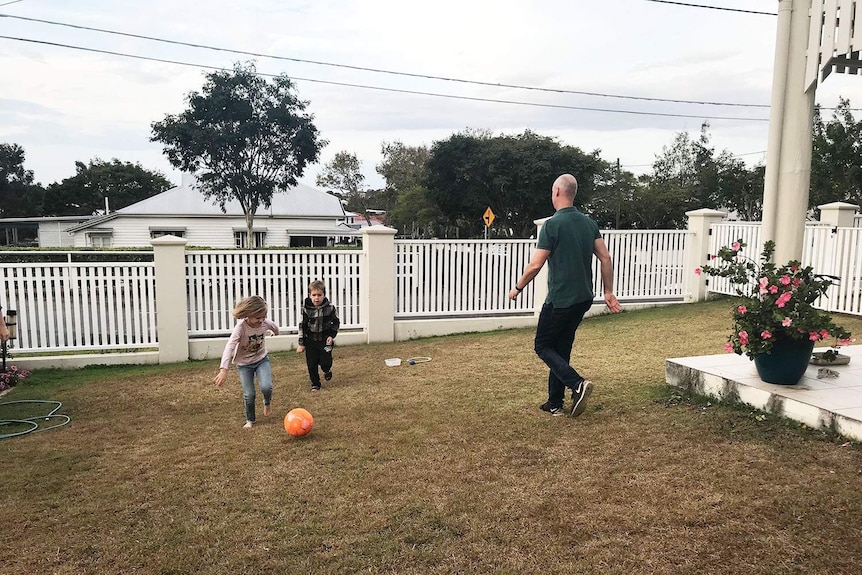 Homeowner Richard Mattsson plays ball with his two children in the yard of their Brisbane home.