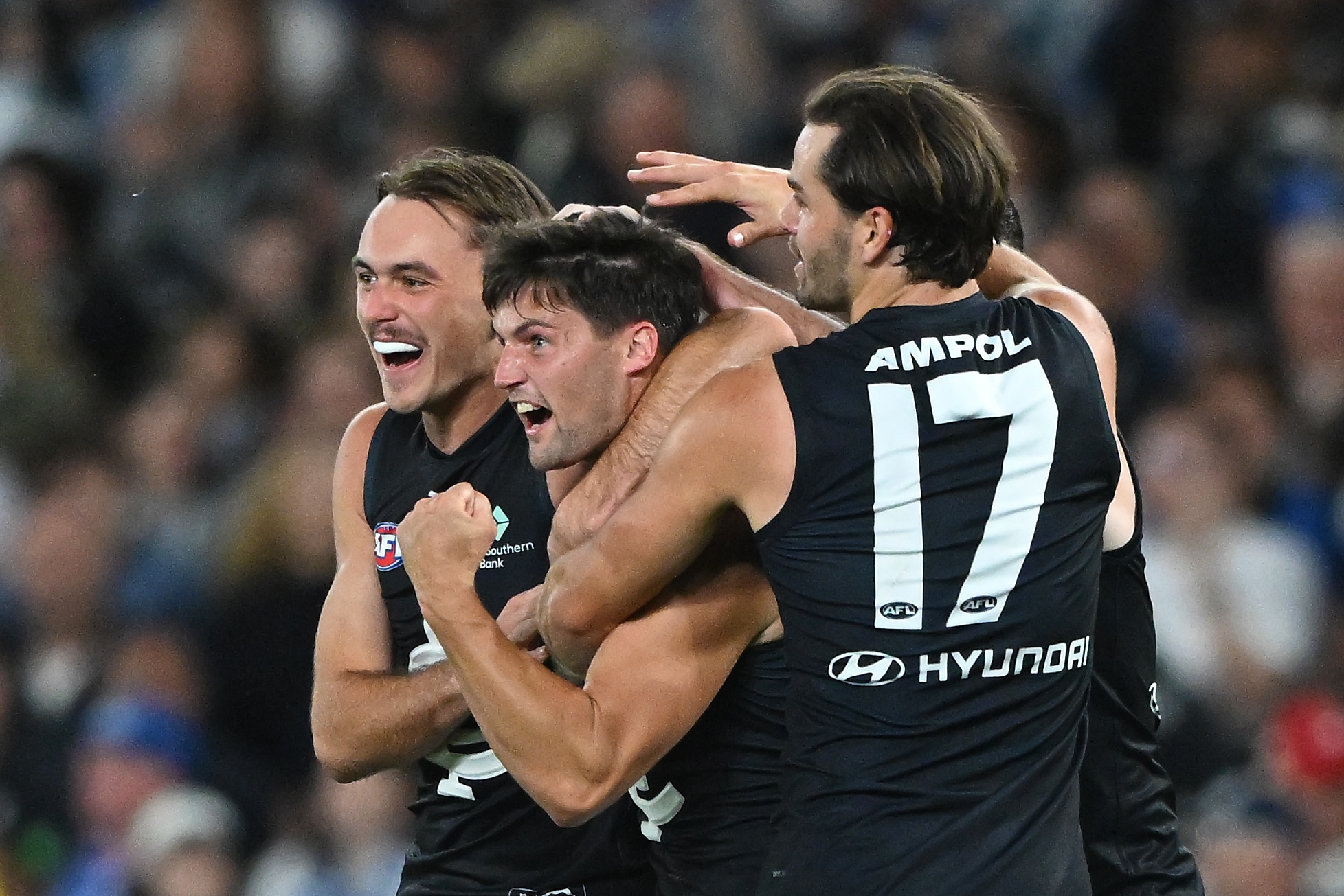 Nic Newman celebrates a goal with two Carlton teammates