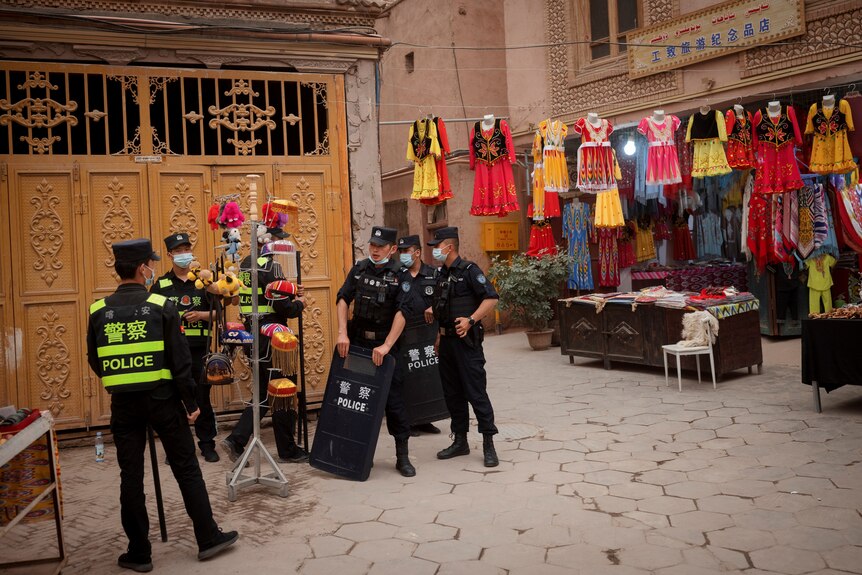 Police officers stand guard next to a shop selling traditional attire