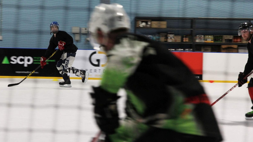 Three players on the rink moving at high speed.