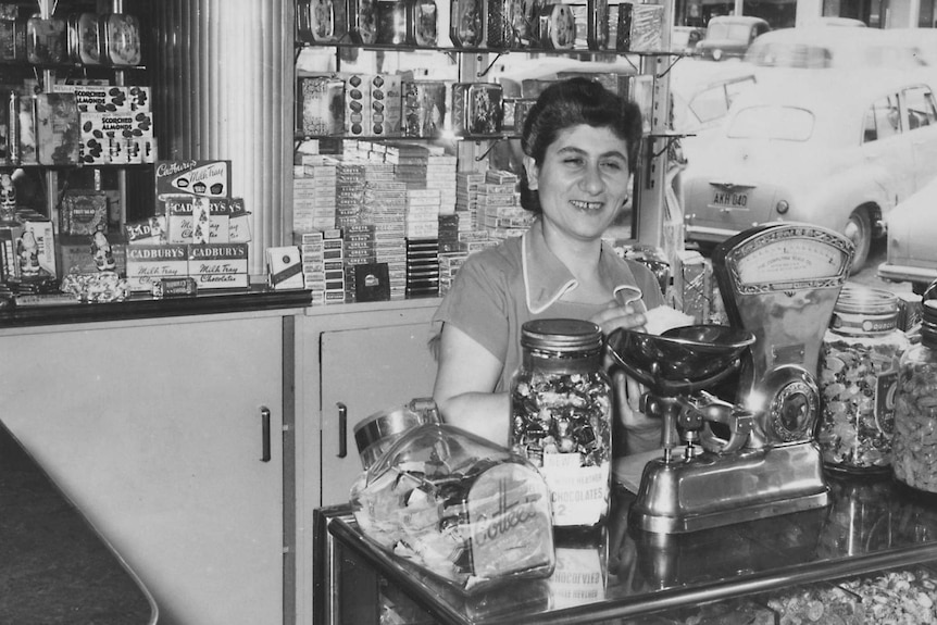 A black and white photo of a Lebanese woman behind the counter in a cafe.