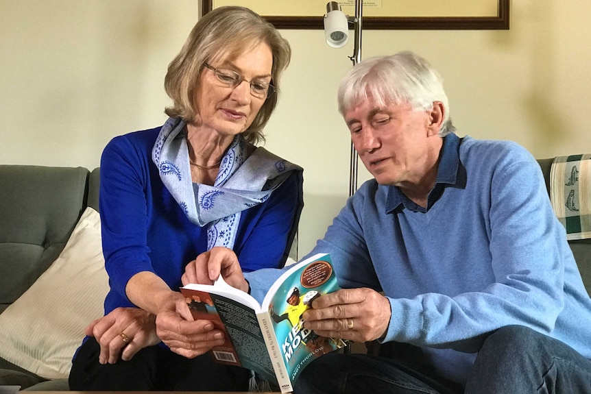 An elderly couple sit reading a book