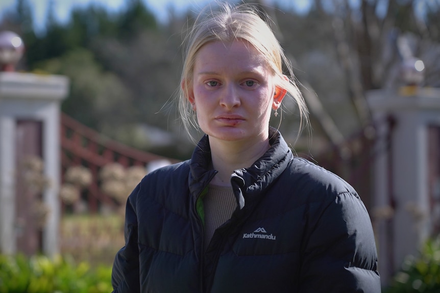 A portrait of a young woman with blonde hair, serious expression