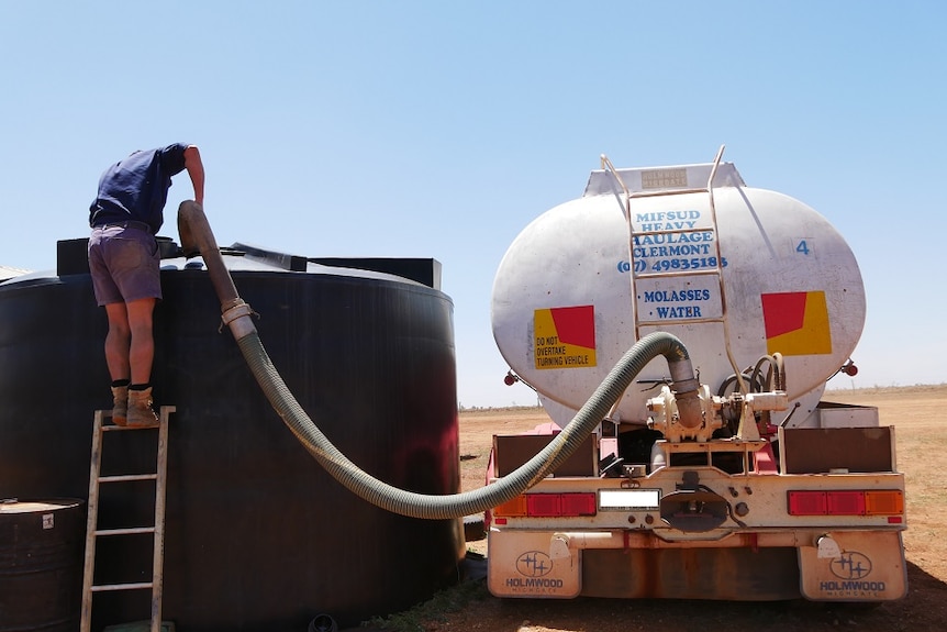 Man pumps molasses from truck into large storage container