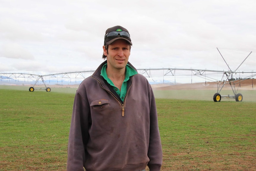 Tasmanian farmer Angus Lyne stands in a paddock facing the camera.