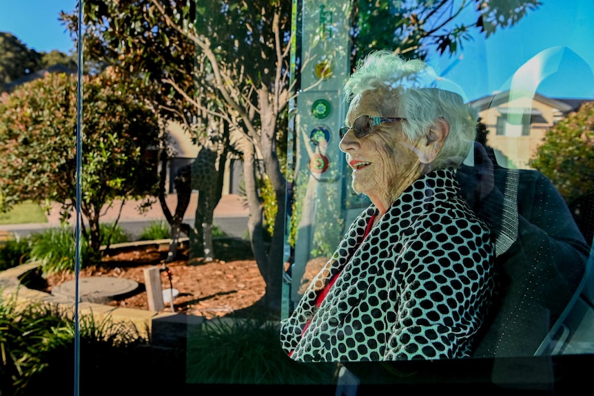 An elderly woman is seen through the window of the BusBot vehicle.