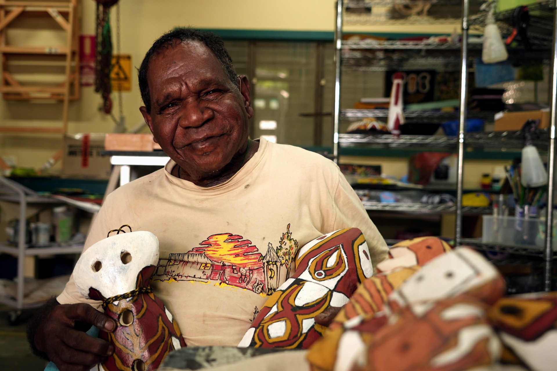 An elderly AboriMan paints a ceramic figure in an art workshop.