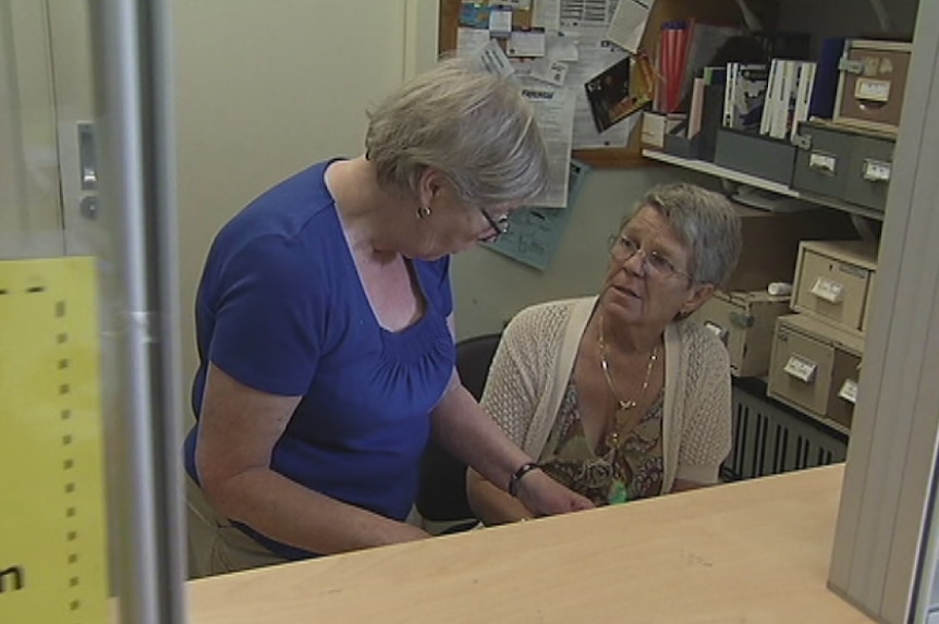 Narelle Morris, manager of Holroyd Community Aid, sits at her desk while having a discussion with a colleague