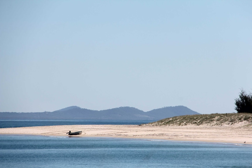 A small boat sits on the sand.