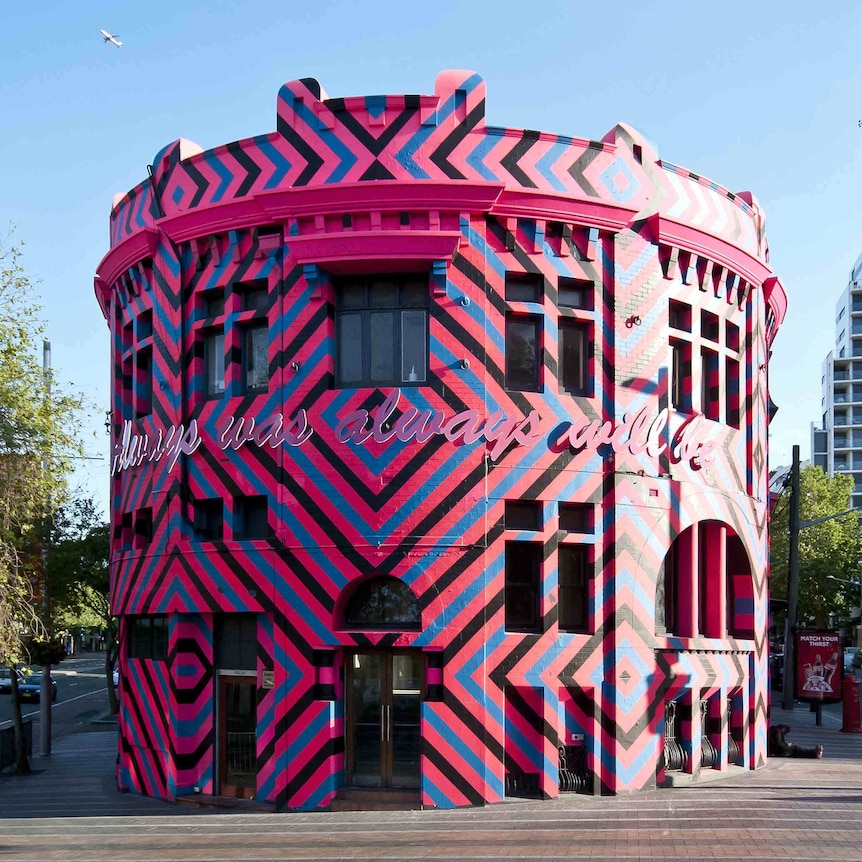 Pink, blue and black geometric artwork covers a curved building.