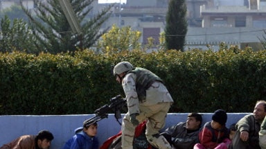 Taking cover: civilians and a US soldier crouch down as shots are fired