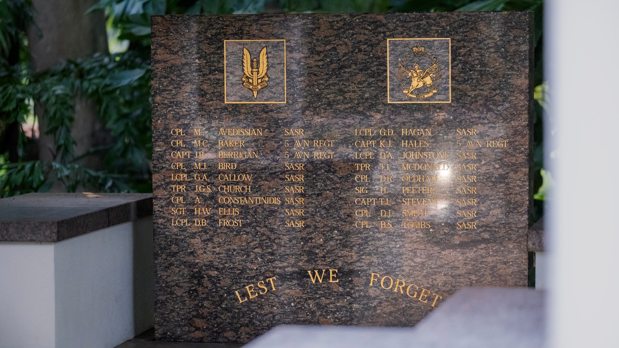 A red stone memorial with  the names of eighteen people in gold lettering.