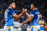 Two Gold Coast Titans NRL players shake hands as they celebrate a try.