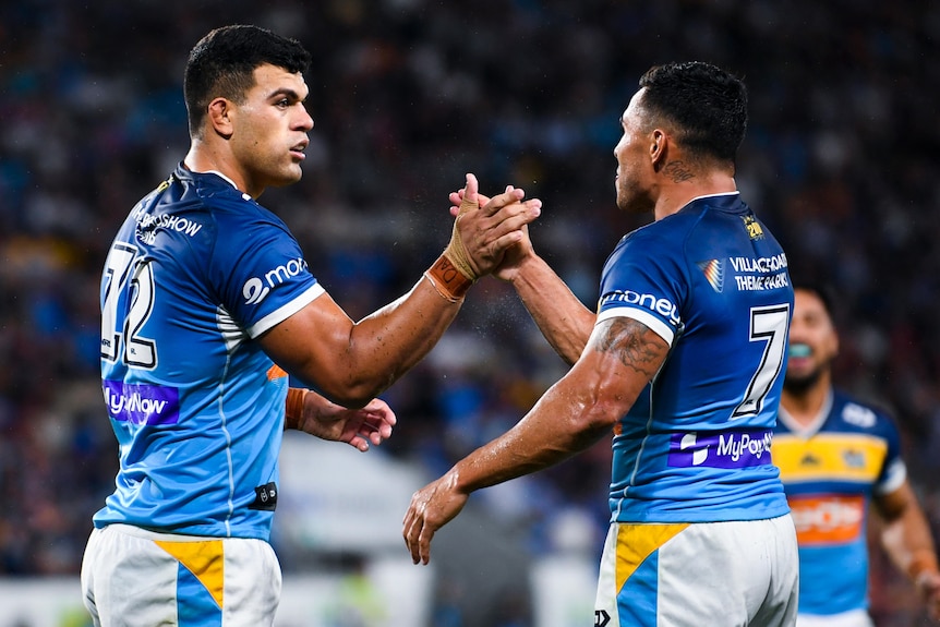 Two Gold Coast Titans NRL players shake hands as they celebrate a try.