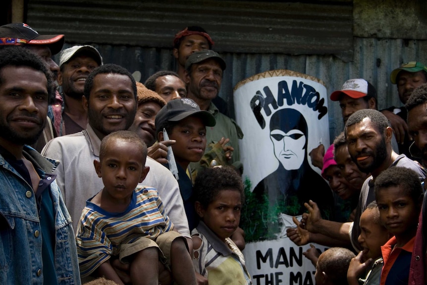 A group of PNG Phantom fans gather aorund a poster of the comic.