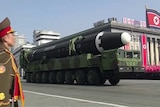 A soldier stands as a truck carrying a missile drives down a Pyongyang street.