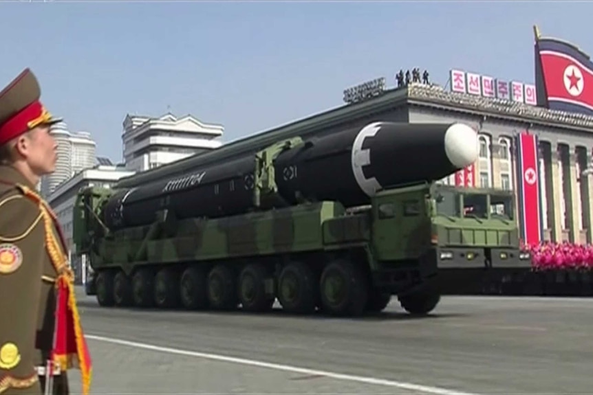 A soldier stands as a truck carrying a missile drives down a Pyongyang street.