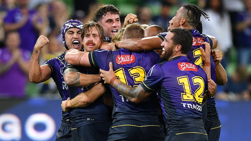 A group of Melbourne Storm NRL players embrace after defeating South Sydney.