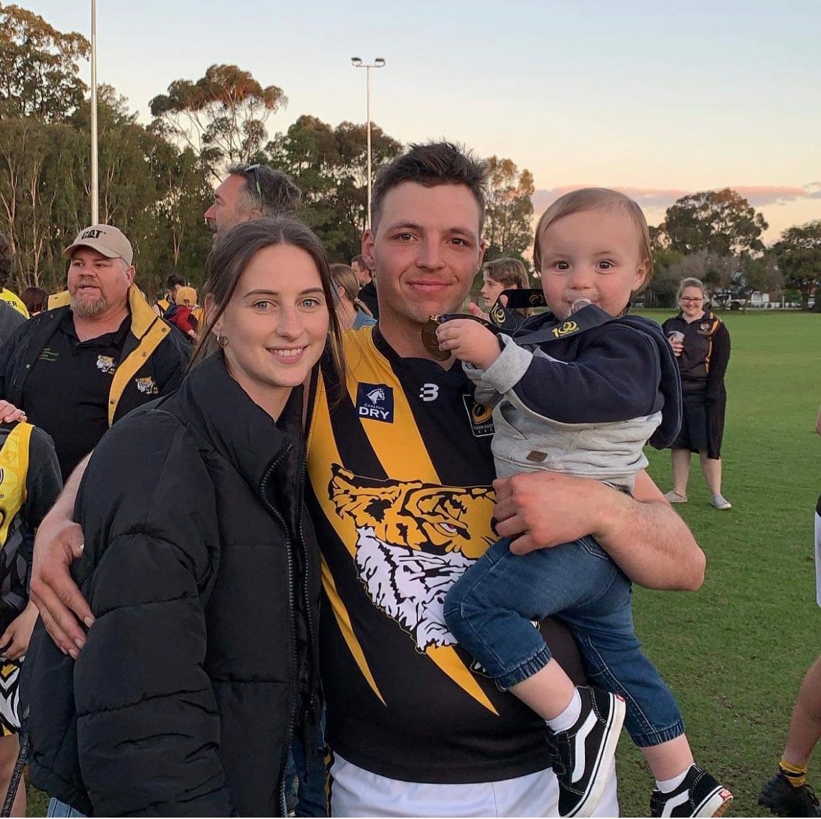 Homem em jumper de futebol com esposa e filho em um oval verde
