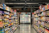A supermarket aisle with grocery staples stacked on shelves on either side.