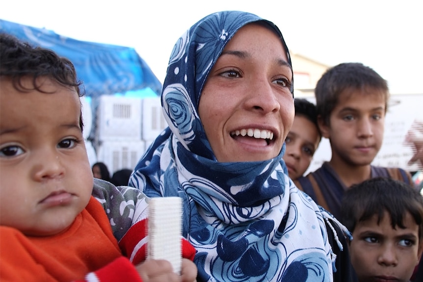 An eighteen-year-old woman holding her young baby.