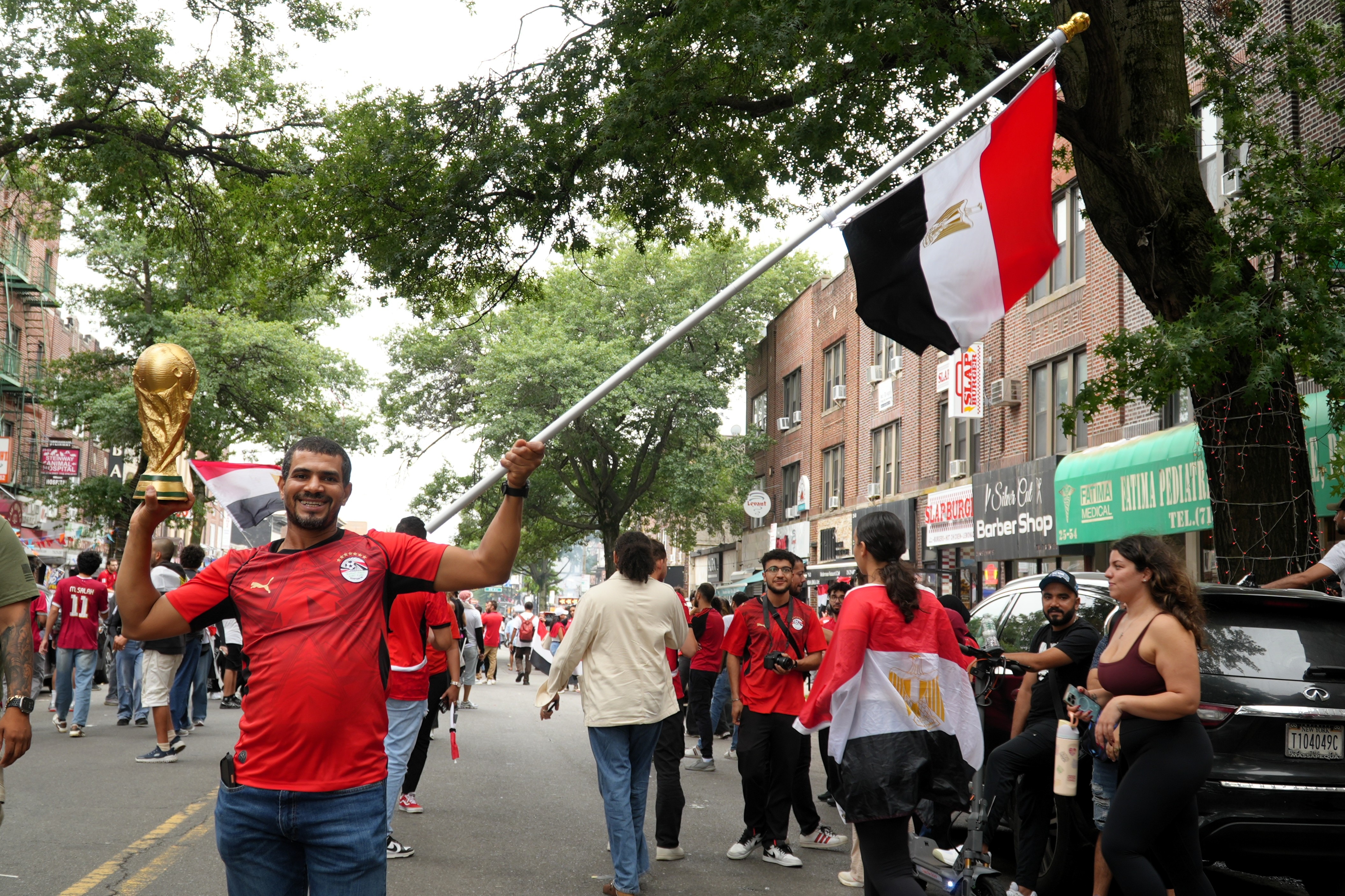 An Egypt fan holds a fake World Cup trophy and waves an Egypt flag