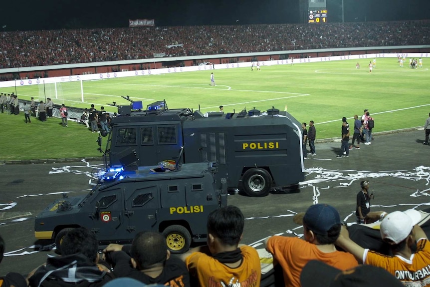 Dua kendaraan polisi dekat lapangan sepak bola