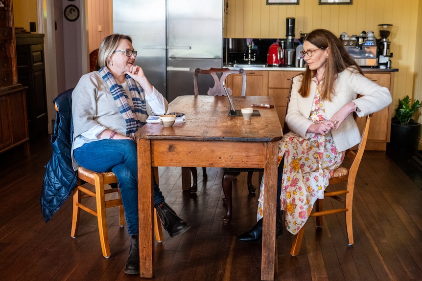 Two women sitting opposite each other at a dining table. 