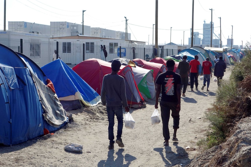 Asylum seekers walk in the northern area of the "Jungle" camp in Calais.