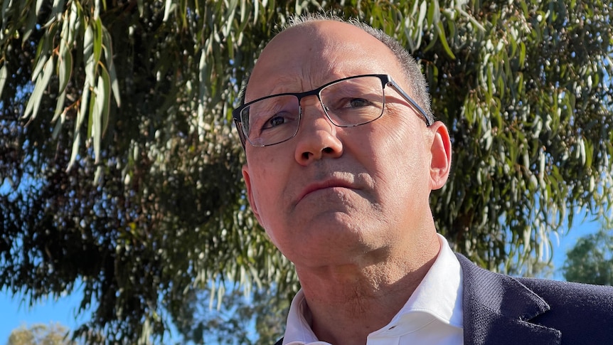 A man wearing a white shirt and blue jacket