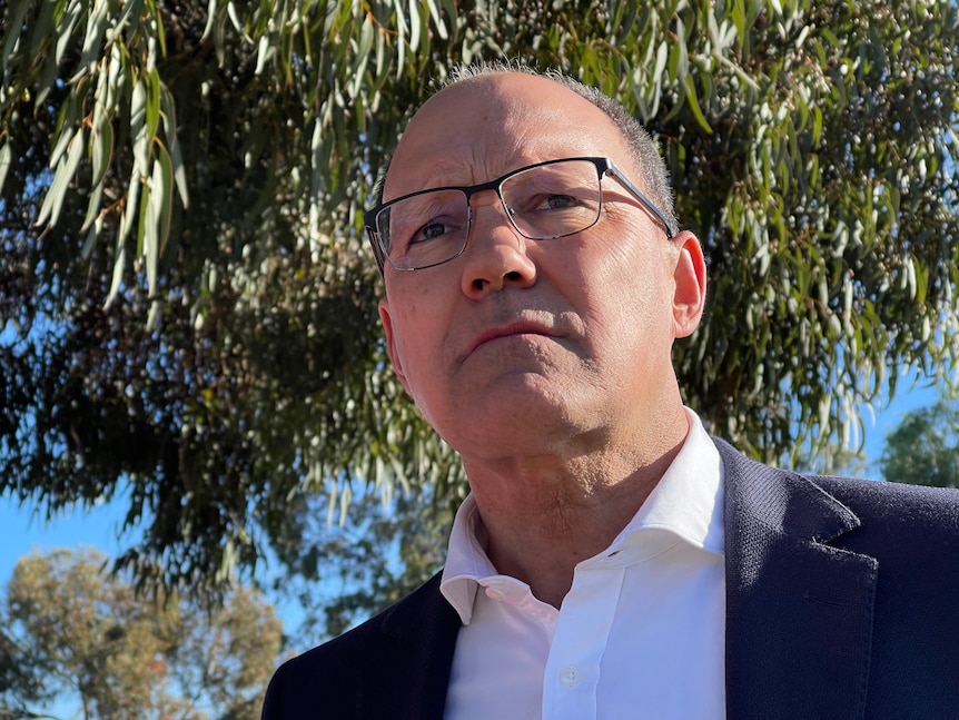 A man wearing a white shirt and blue jacket