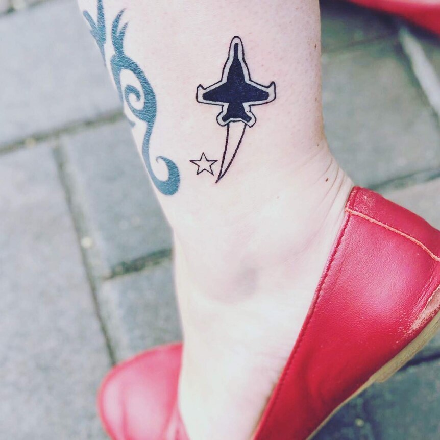 A woman's leg with a tattoo of a jet and a star on it