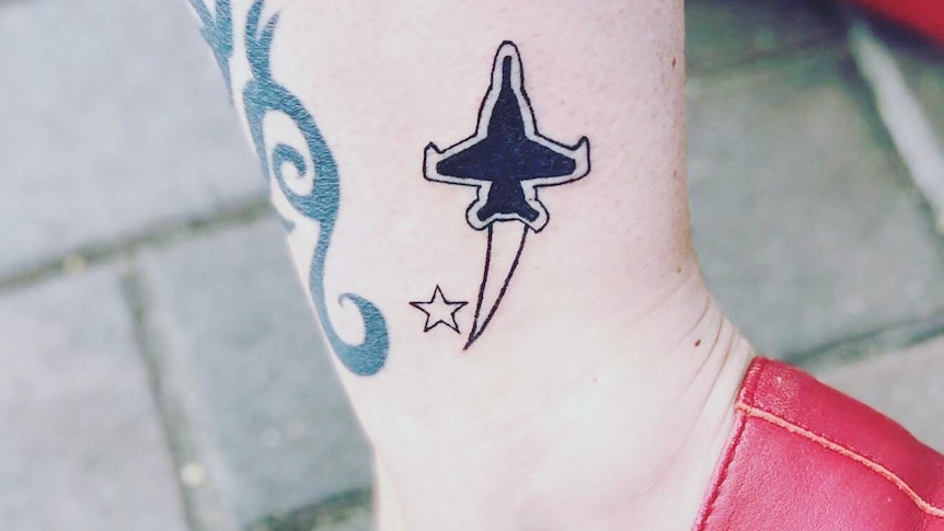 A woman's leg with a tattoo of a jet and a star on it