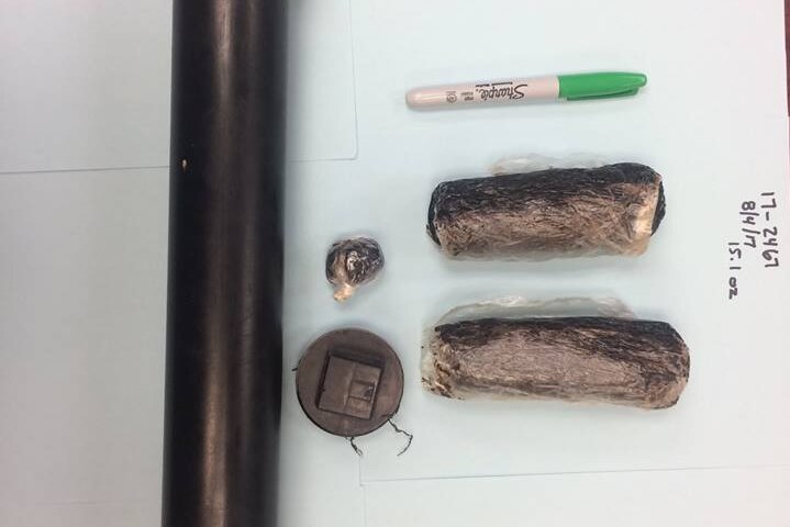 The contents of a container dug up by a dog, 15 ounces of black tar heroin, laid out of a white background.