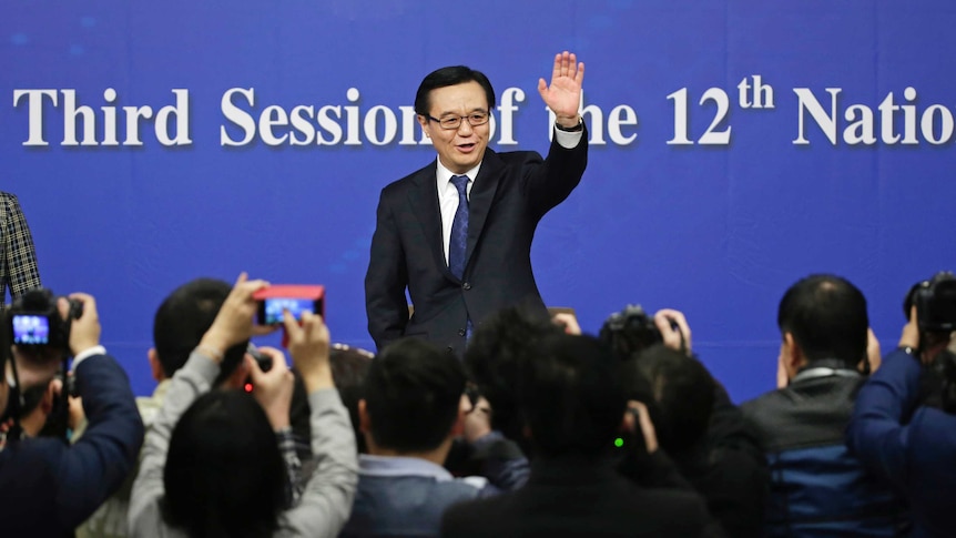 China's Minister of Commerce Gao Hucheng waves to the media as he arrives for a news conference