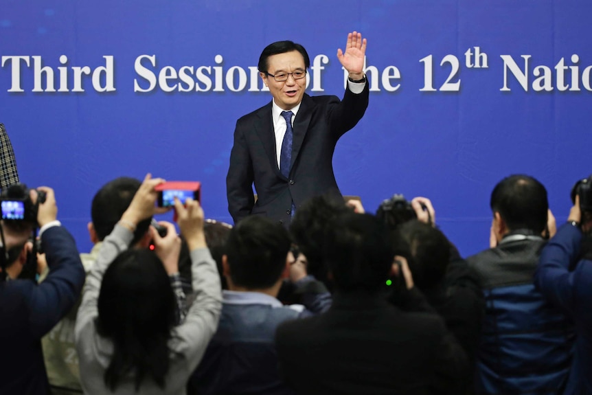 China's Minister of Commerce Gao Hucheng waves to the media as he arrives for a news conference