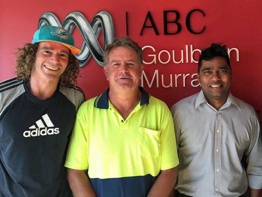 Three men stand infront of a red wall with ABC Goulburn Murray logo behind them