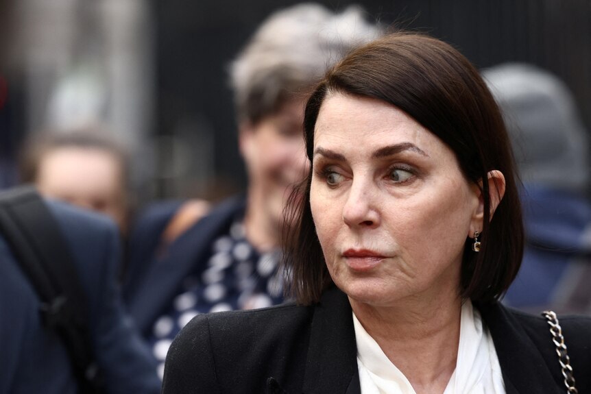 Sadie Frost looks sideways to her right as she walks along a street. She has a stern look on her face.