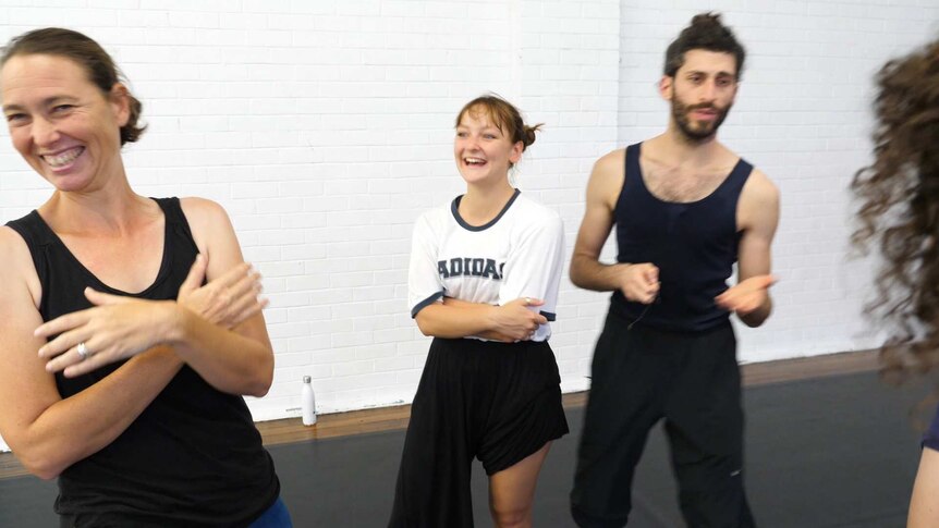 Informal grouping of three dancers standing around laughing and talking