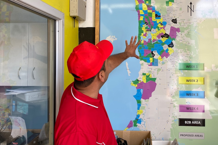 A man looking at a colourful map of Perth suburbs.