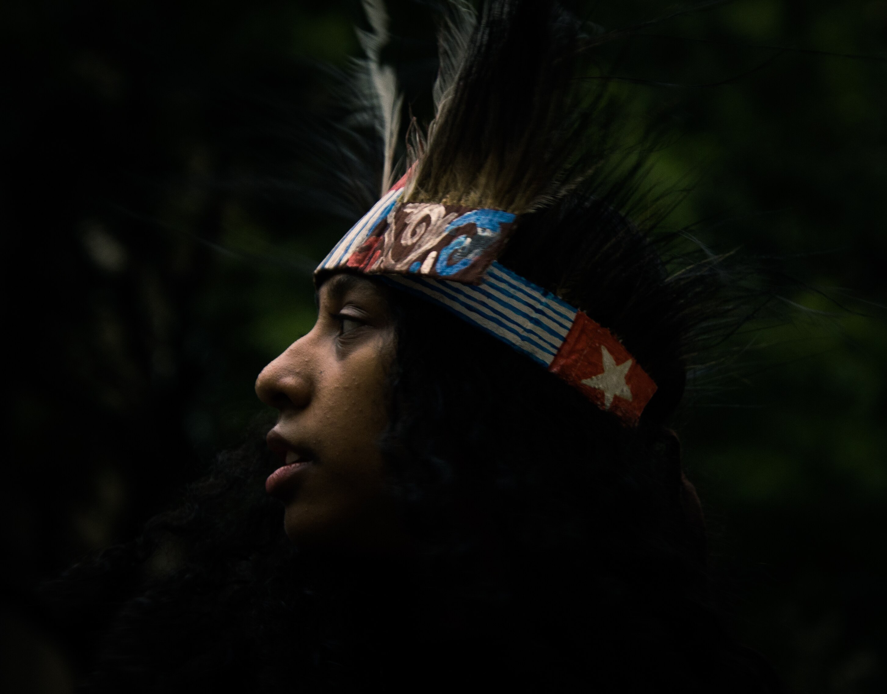 Side profile of young boy in feathered headdress
