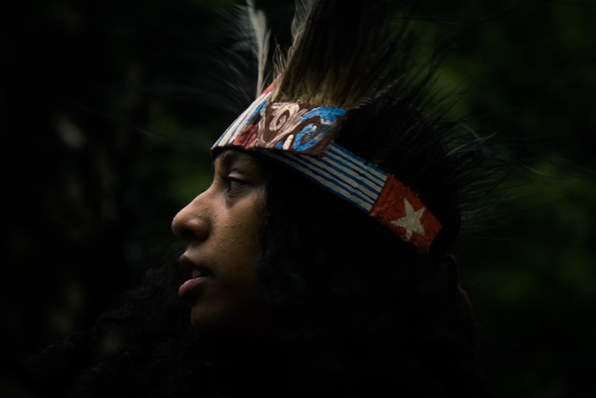 Side profile of young boy in feathered headdress